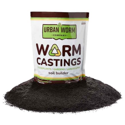 A white plastic pack containing nutrient-rich worm castings rests on dark, fertile soil, ready to nourish plants. The contrast between the bright packaging and the earthy soil highlights the organic essence of the natural fertilizer.